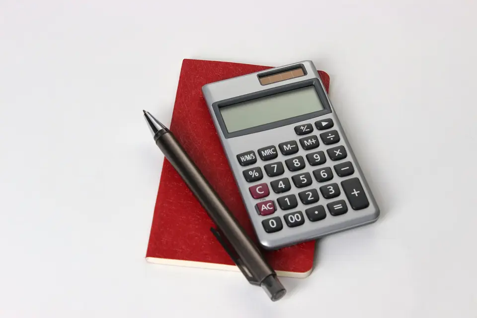 Rekenmachine en pen op een rood notitieboek